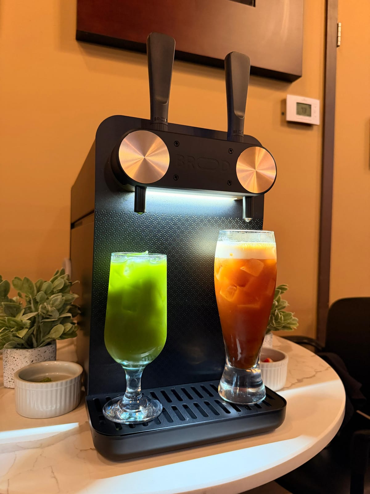 A vivid green nitro matcha and an iced Thai-style tea served side by side on the nitro tap