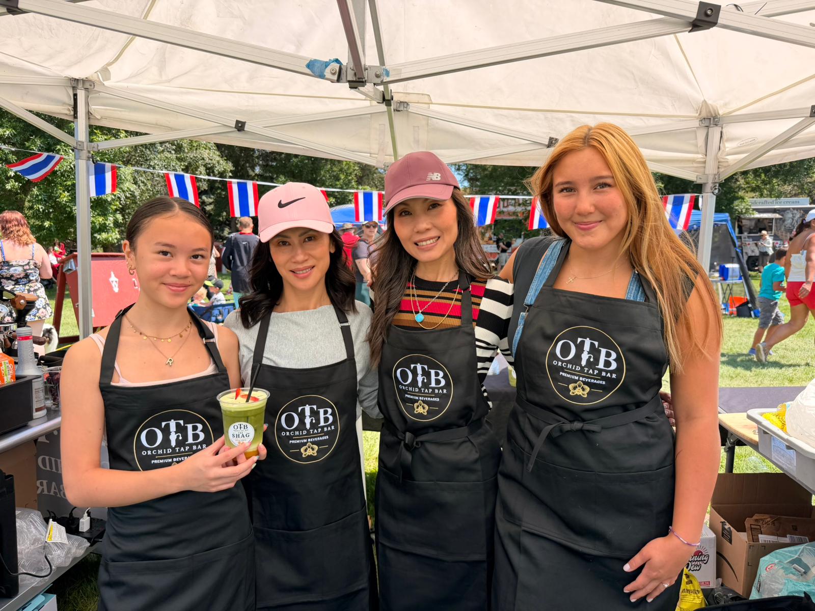 Four members of the family team in OTB aprons smiling together at the booth