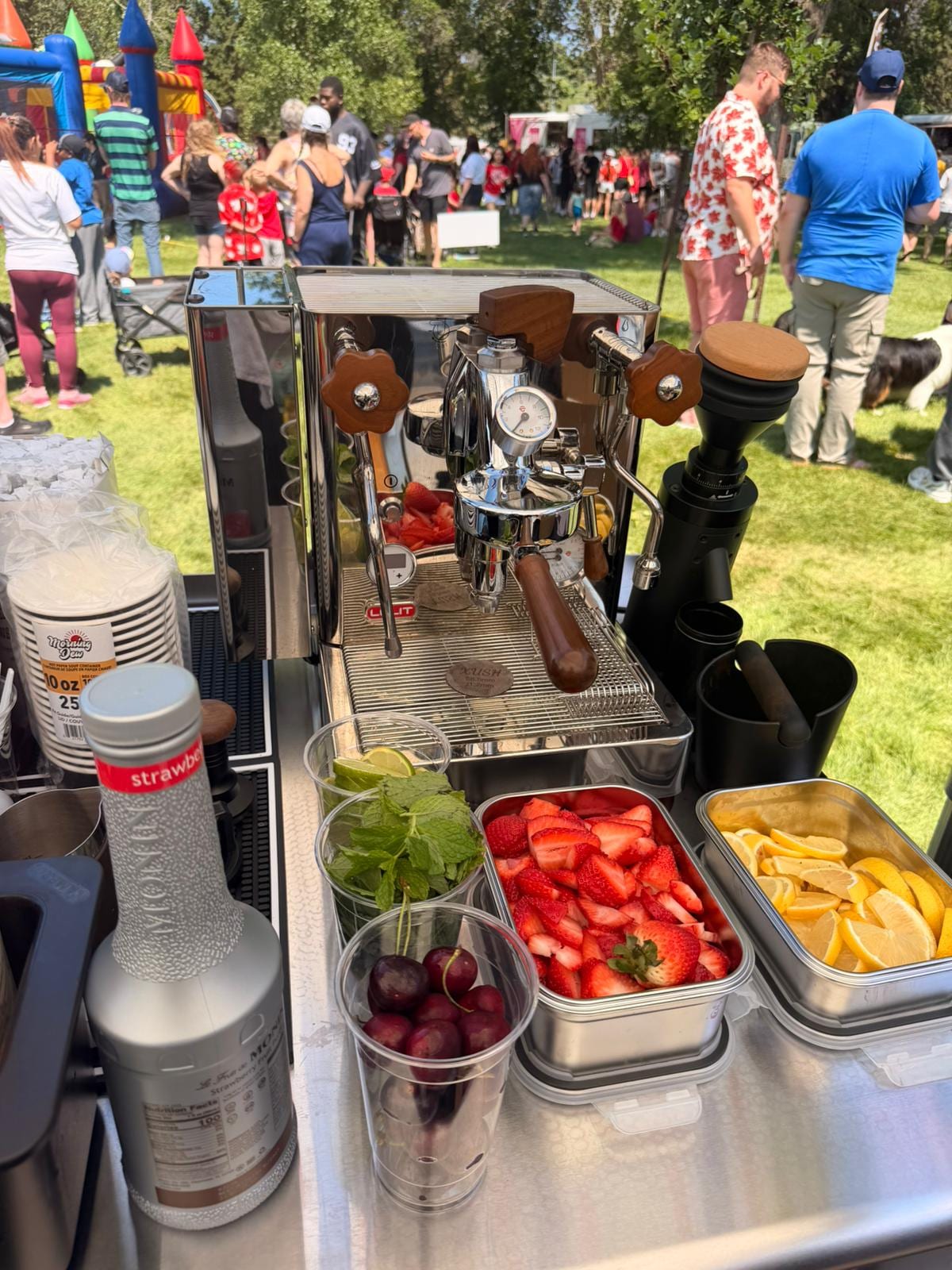 Fresh strawberries, lemons, cherries, and mint prepped beside the espresso machine at the booth