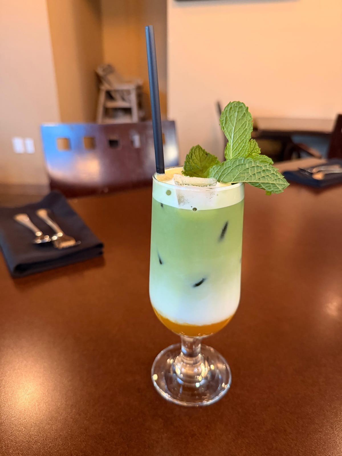 Tall nitro matcha latte with a creamy head and fresh mint garnish