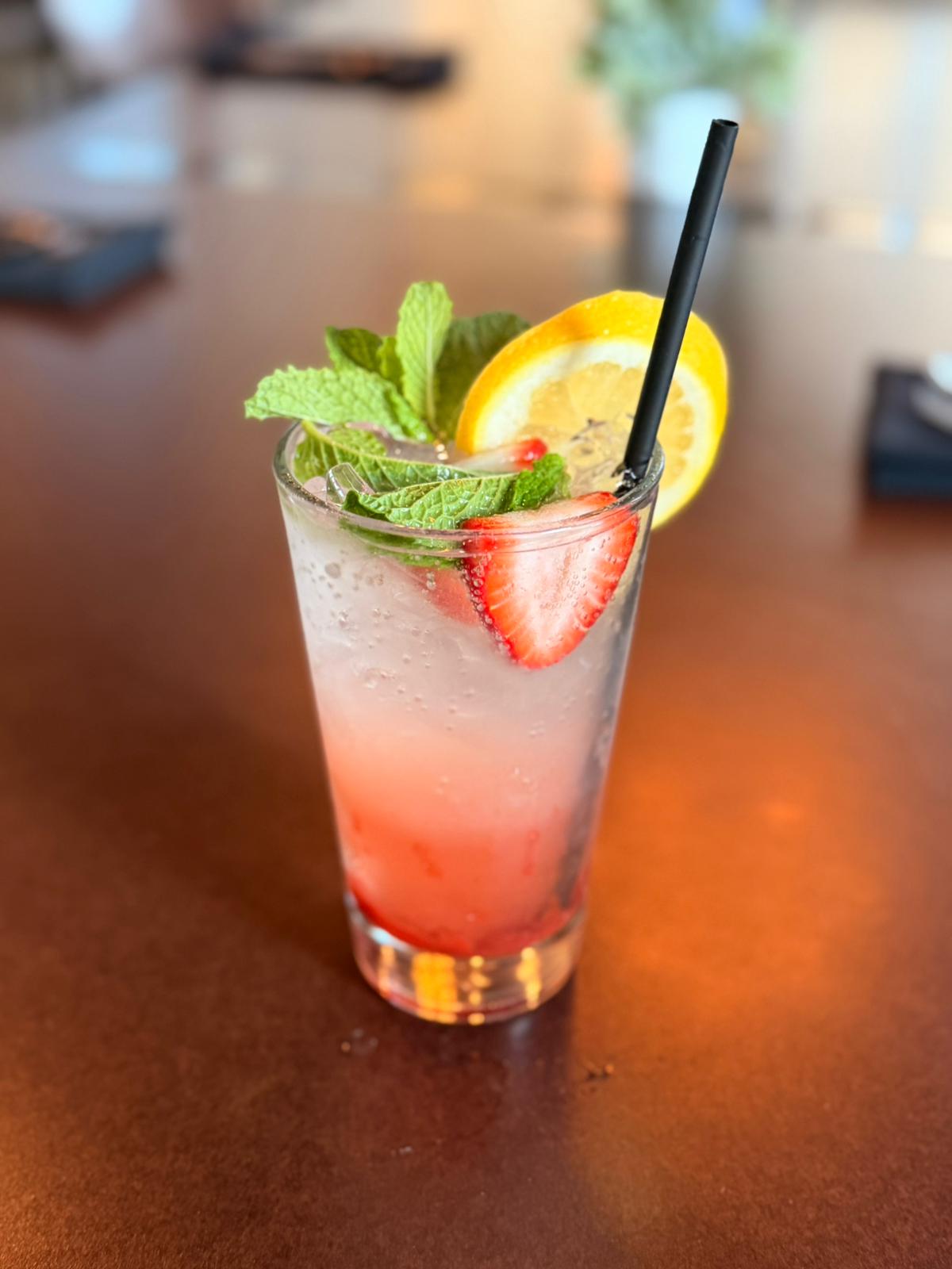 A tall glass of Orchid Tap Bar's signature Shag strawberry lemonade with fresh mint and an orange wheel